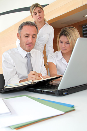 people planning in a notebook in front of a laptop
